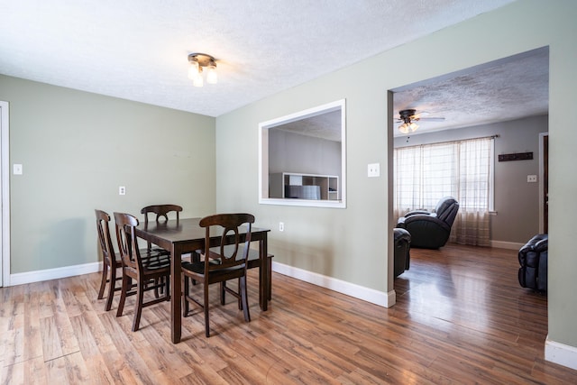 dining space featuring a textured ceiling, baseboards, and wood finished floors