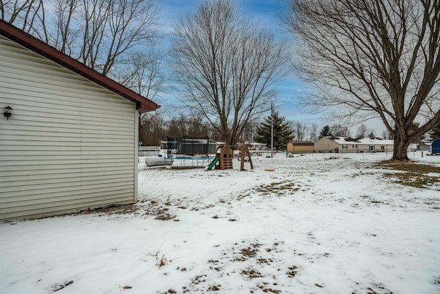 yard layered in snow with a trampoline and a playground