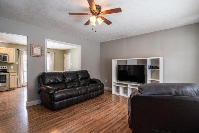 living room with a textured ceiling, wood finished floors, and baseboards