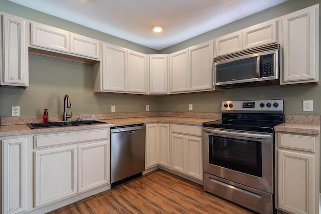 kitchen featuring appliances with stainless steel finishes, white cabinets, light countertops, and a sink