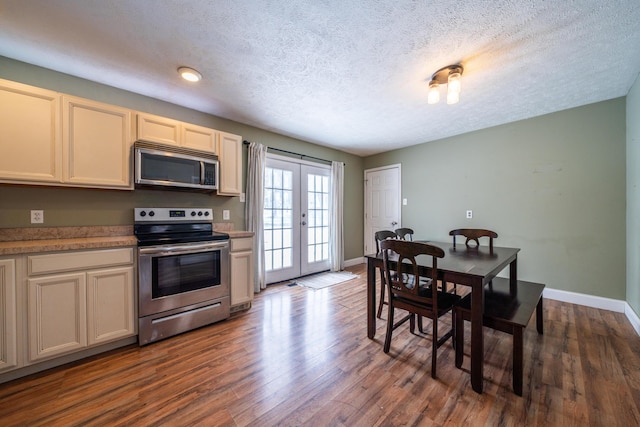 kitchen featuring dark wood-style floors, appliances with stainless steel finishes, cream cabinets, light countertops, and french doors