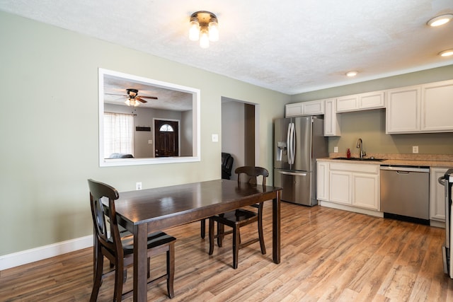 dining space with a textured ceiling, recessed lighting, baseboards, and light wood-style floors