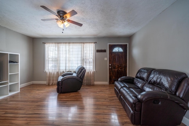 living area with a textured ceiling, baseboards, and dark wood-style flooring