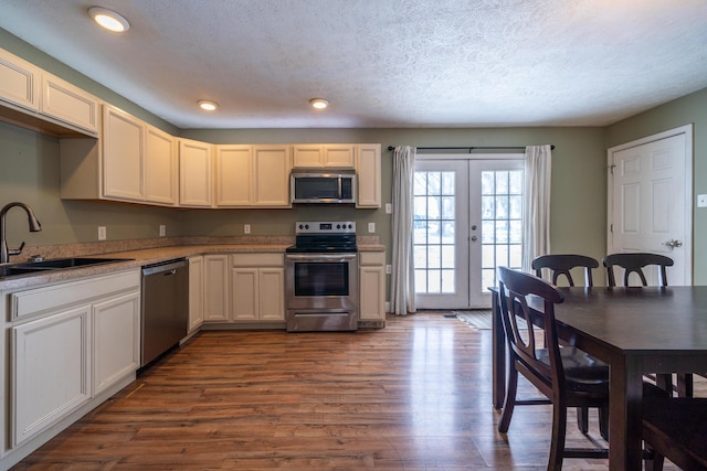 kitchen featuring dark wood-style floors, appliances with stainless steel finishes, light countertops, french doors, and a sink