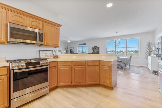 kitchen featuring stainless steel appliances, decorative light fixtures, a chandelier, and light hardwood / wood-style floors