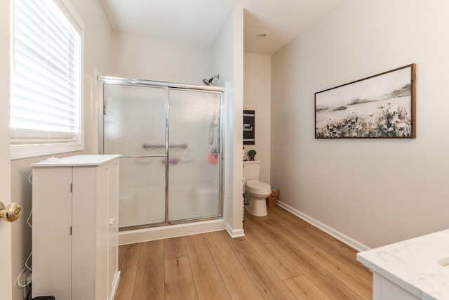 bathroom featuring hardwood / wood-style flooring, toilet, a wealth of natural light, and walk in shower