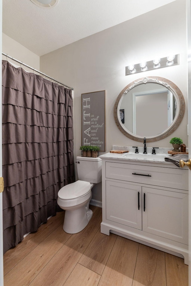 bathroom featuring wood-type flooring, vanity, and toilet