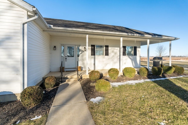 entrance to property featuring a porch and a lawn