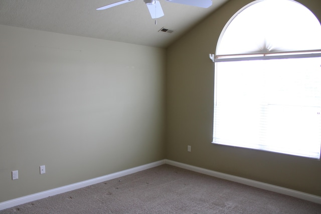 empty room featuring ceiling fan, lofted ceiling, light carpet, visible vents, and baseboards