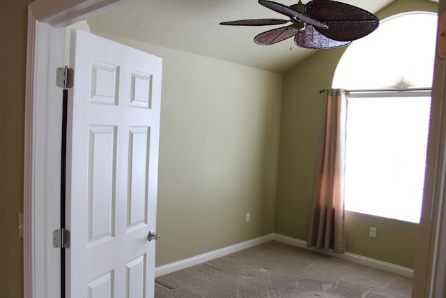 spare room with light carpet, ceiling fan, vaulted ceiling, and baseboards