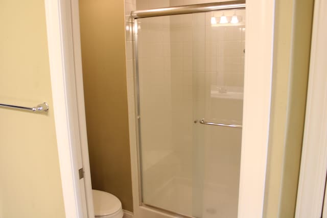 bathroom featuring toilet and a shower stall