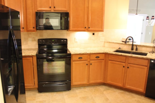 kitchen with tasteful backsplash, a sink, black appliances, and light stone countertops