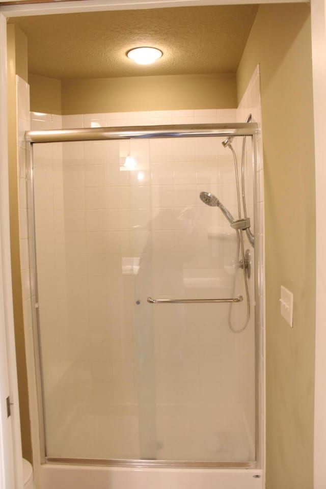 full bathroom featuring a textured ceiling, a shower stall, and toilet