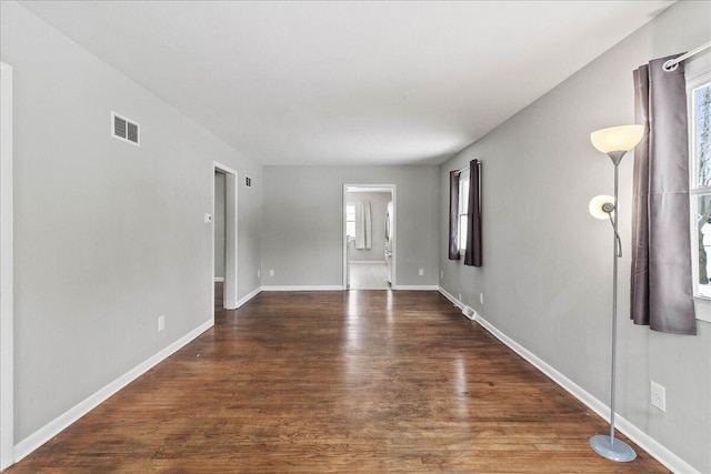 spare room with wood finished floors, visible vents, baseboards, and a healthy amount of sunlight