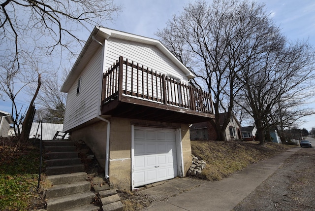 view of side of home featuring a garage, a wooden deck, and stairs