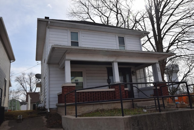 american foursquare style home featuring a porch and brick siding