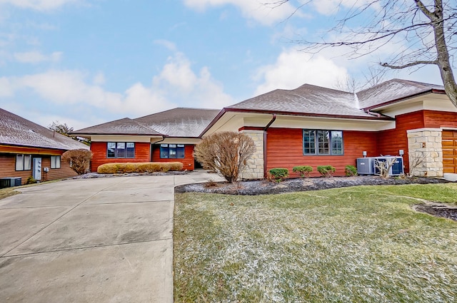 view of front of home featuring stone siding, a front lawn, and central air condition unit