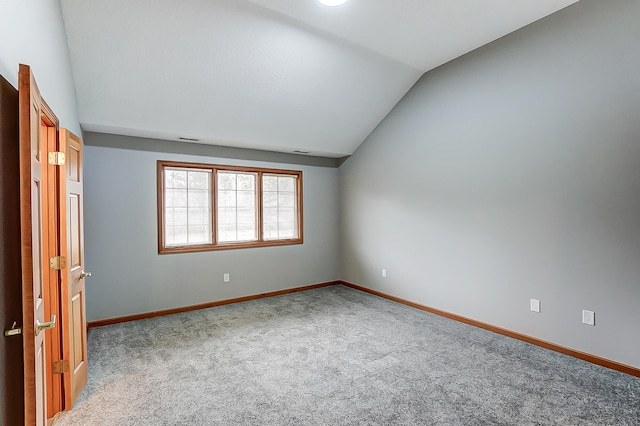 unfurnished room featuring lofted ceiling, carpet, visible vents, and baseboards