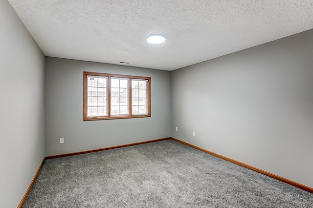 unfurnished room with a textured ceiling, carpet floors, and baseboards