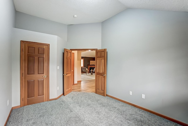 bedroom featuring light carpet, vaulted ceiling, and baseboards