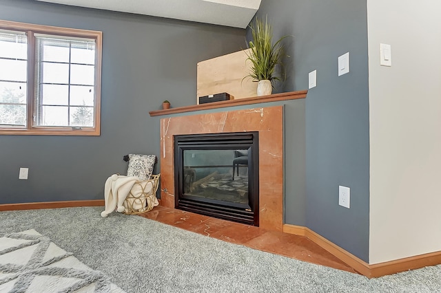 interior space featuring carpet floors, a fireplace with flush hearth, and baseboards