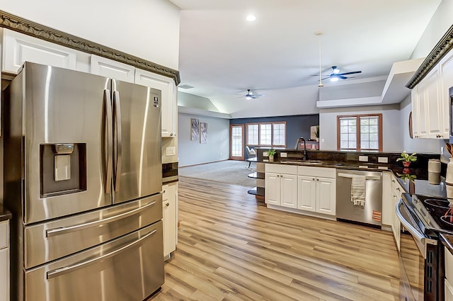 kitchen with dark countertops, appliances with stainless steel finishes, white cabinets, a sink, and a peninsula