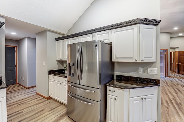 kitchen with vaulted ceiling, light wood finished floors, white cabinets, and stainless steel fridge with ice dispenser