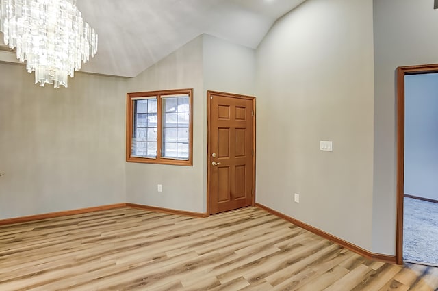 entrance foyer featuring light wood-style floors, baseboards, vaulted ceiling, and an inviting chandelier