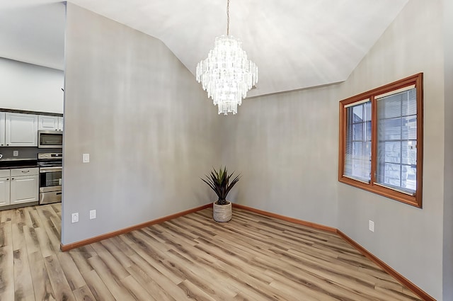 unfurnished dining area with lofted ceiling, light wood-style floors, baseboards, and a chandelier