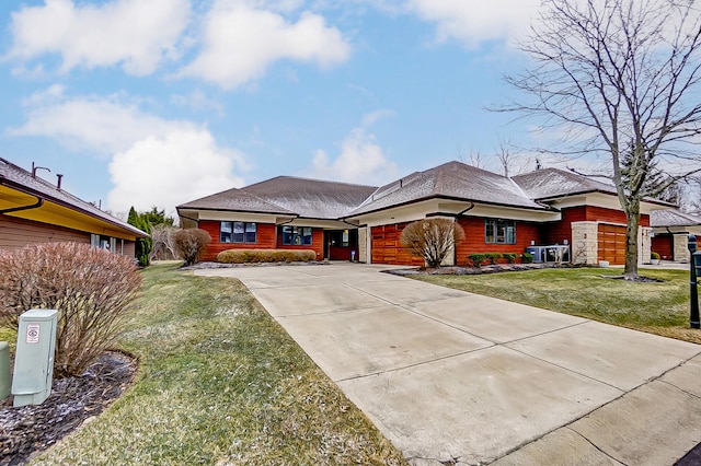 view of front of property featuring a garage, concrete driveway, and a front lawn