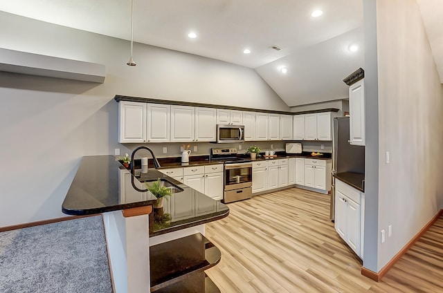 kitchen featuring dark countertops, appliances with stainless steel finishes, a sink, a peninsula, and a kitchen bar