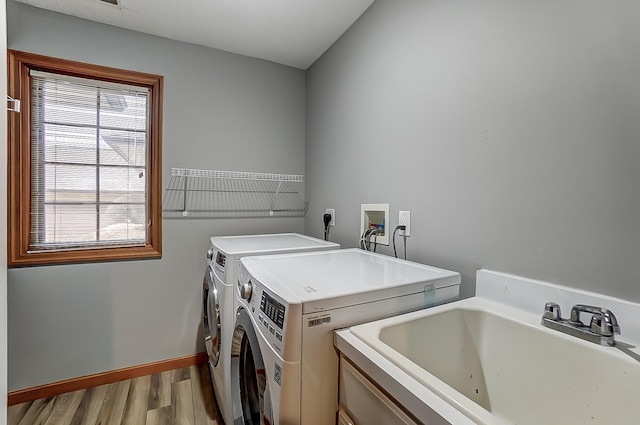 laundry area with laundry area, baseboards, washer and dryer, light wood-type flooring, and a sink