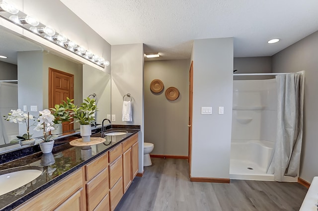 bathroom featuring a stall shower, a textured ceiling, a sink, and wood finished floors