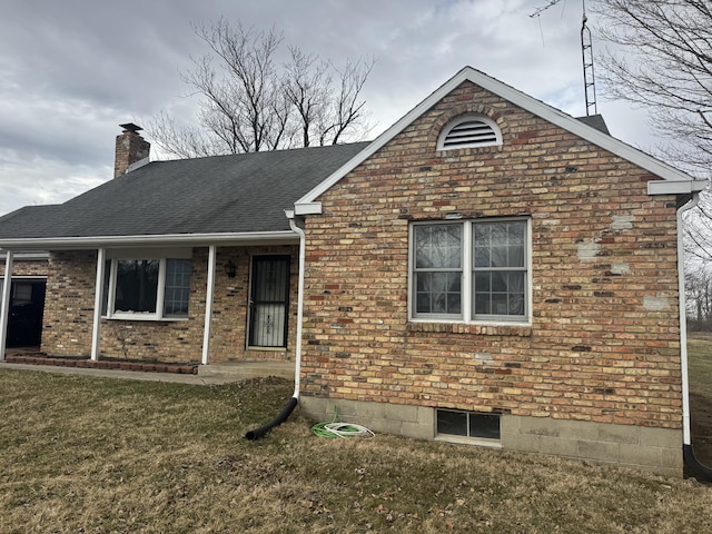 view of front facade featuring roof with shingles, brick siding, a chimney, and a front lawn