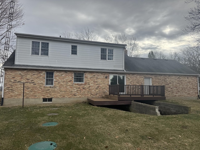 back of property with a deck, a lawn, and brick siding