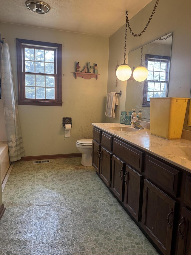 bathroom featuring a healthy amount of sunlight, a sink, toilet, and double vanity