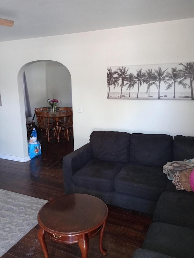 living area featuring arched walkways and wood finished floors