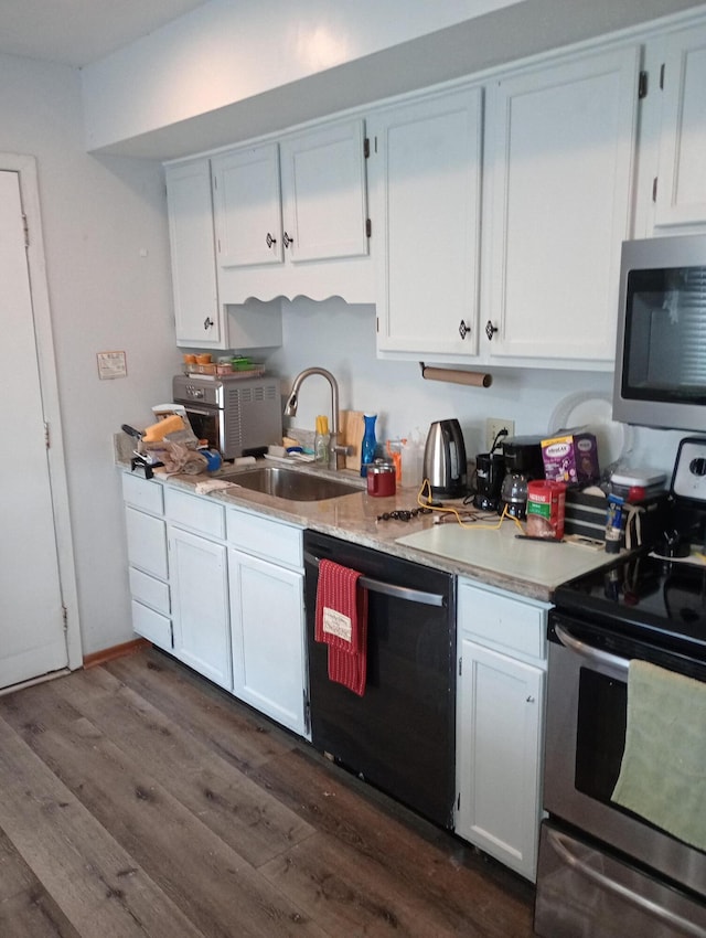 kitchen featuring stainless steel appliances, dark wood-style flooring, a sink, white cabinets, and light countertops