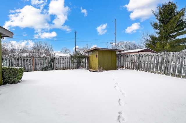 yard covered in snow featuring a storage shed, an outdoor structure, and fence