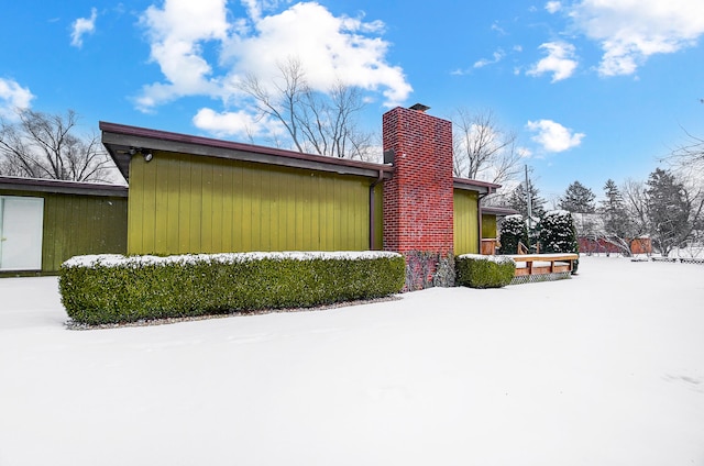 view of snow covered exterior with a chimney