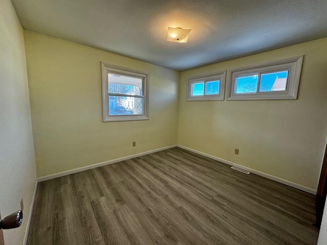 spare room featuring dark wood-type flooring and a textured ceiling