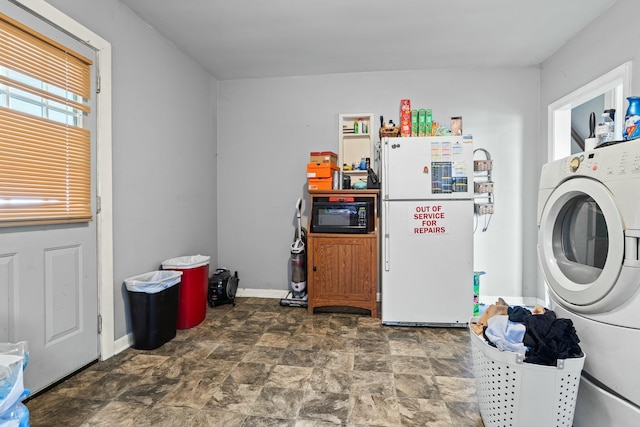 laundry area featuring stone finish flooring, washer / clothes dryer, laundry area, and baseboards