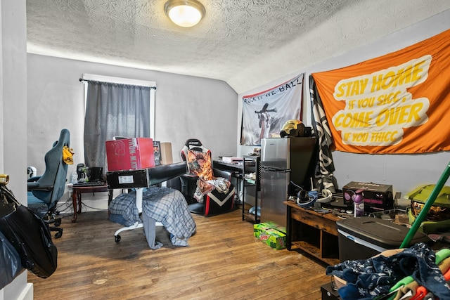 bedroom with hardwood / wood-style floors, vaulted ceiling, and a textured ceiling