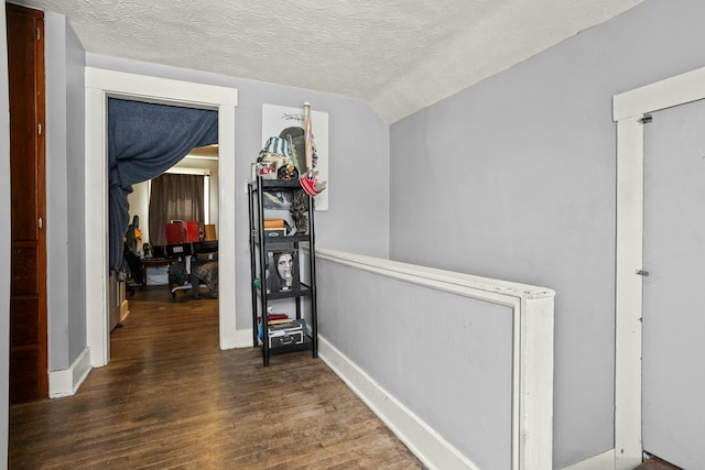 corridor featuring a textured ceiling, baseboards, and wood finished floors