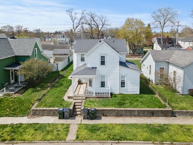 view of front facade with a shingled roof, a fenced backyard, a residential view, and a front lawn