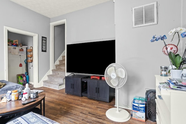 living area featuring wood finished floors, visible vents, and stairs