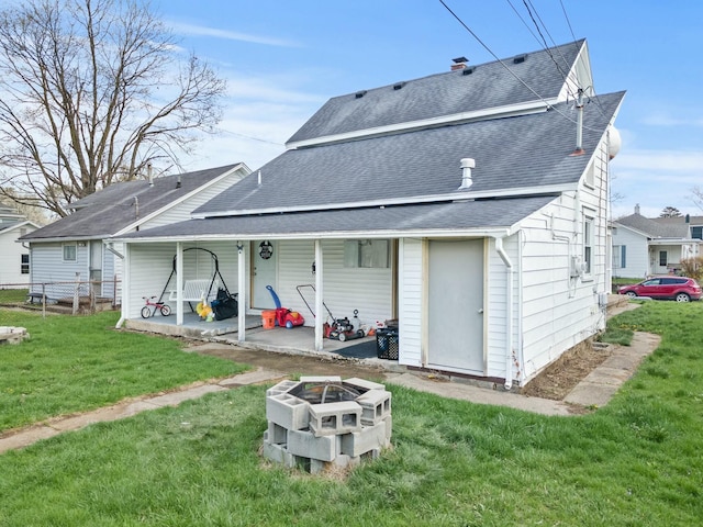 rear view of property featuring roof with shingles, a patio area, and a lawn