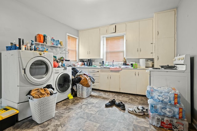 laundry area with a sink, washer and clothes dryer, cabinet space, and stone finish floor