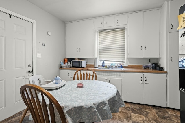 kitchen featuring a sink, white cabinetry, and stone finish flooring