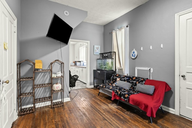 bedroom featuring wood-type flooring, ensuite bathroom, baseboards, and a textured ceiling